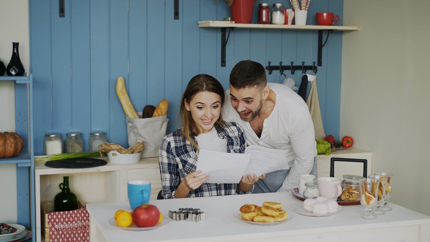 A couple in their kitchen reading a printed report together